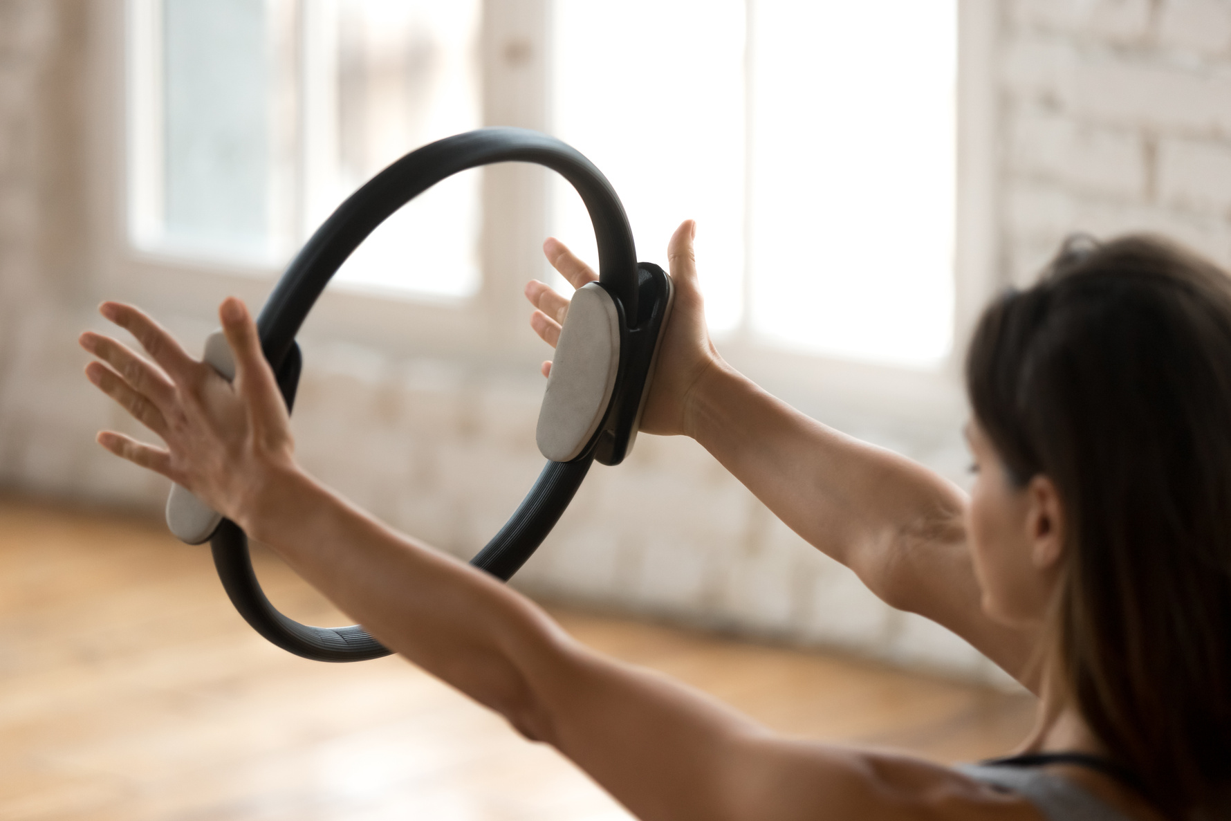 Young sporty woman practicing fitness exercise with a pilates ring